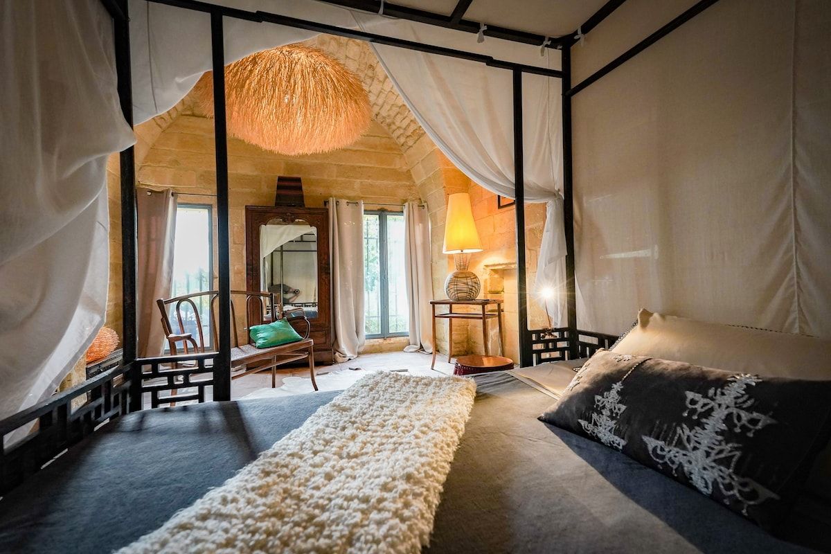 La chambre Chapelle, a canopied bed beneath a high vaulted ceiling